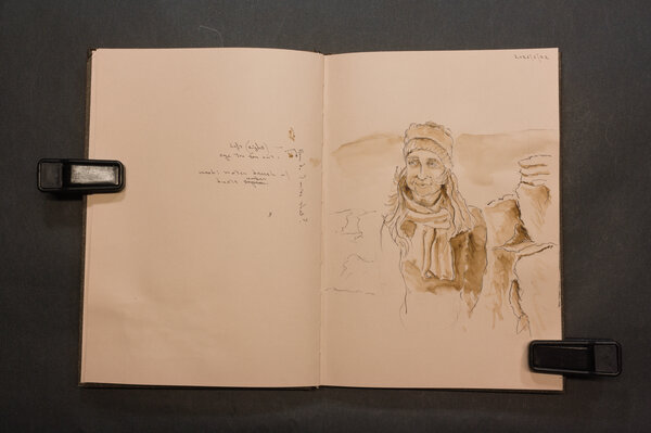 Older woman with knitted scarf by a Scottish rocky and grassy hill, pen and sepia toned wash.